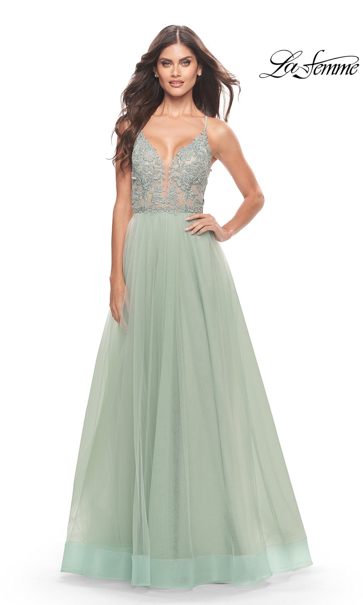 A woman models the Lace-Bodice Long A-Line Prom Dress (La Femme 31542), featuring a light green tulle skirt, embroidered lace bodice, and deep V neckline, standing against a white background with
